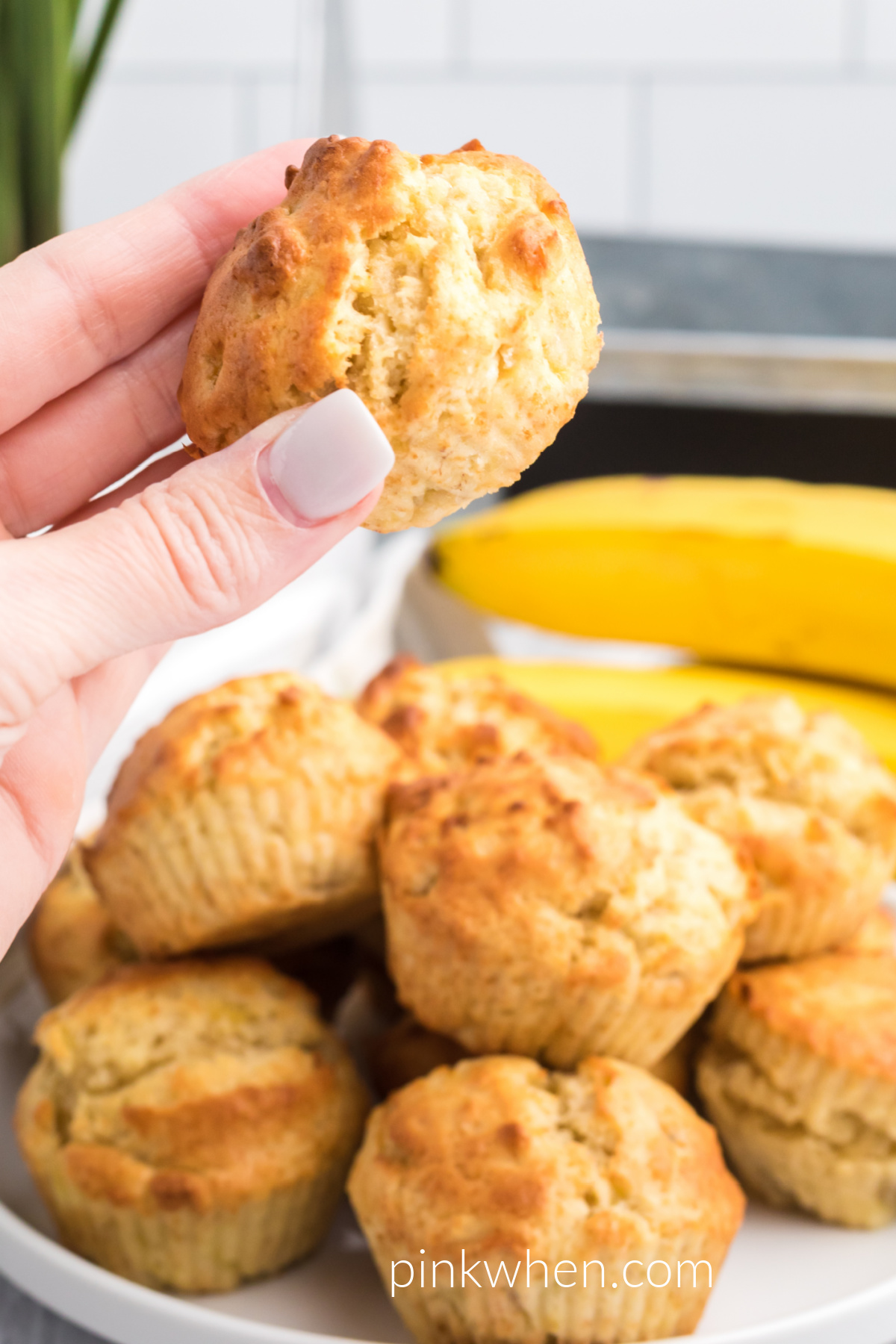 Air Fryer Banana Muffins on a plate and one being held in hand ready to eat. 