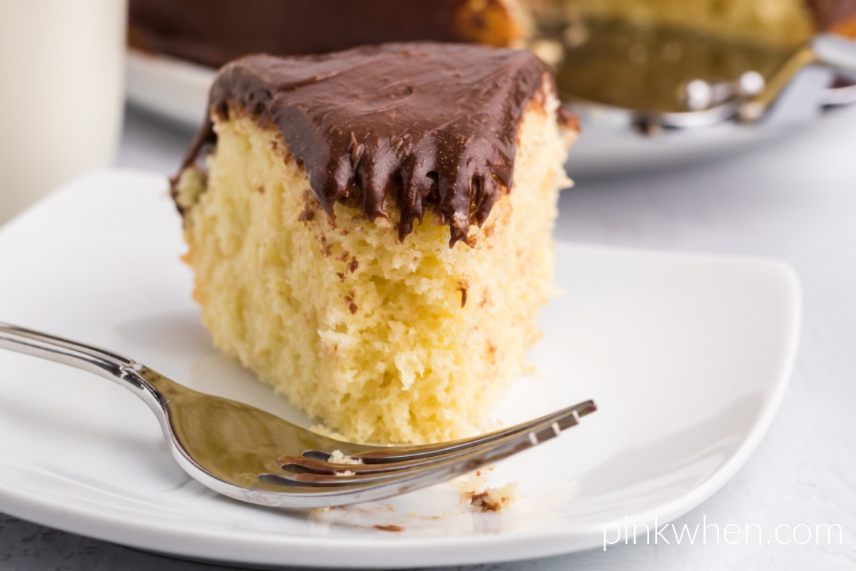 Close up of a slice of air fryer cake with chocolate frosting, missing a bite. 