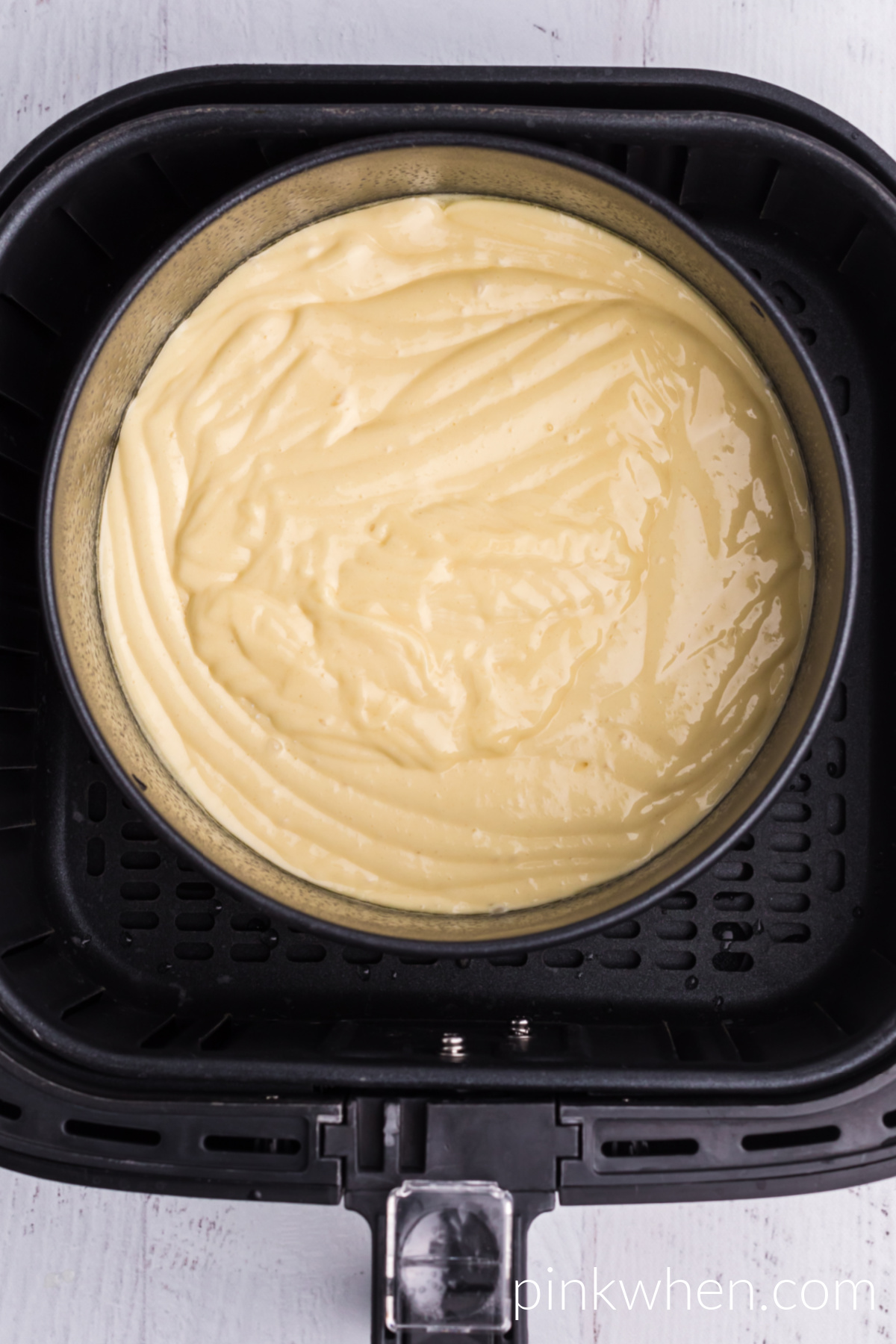 Air Fryer cake pan with batter in the air fryer basket ready to cook. 