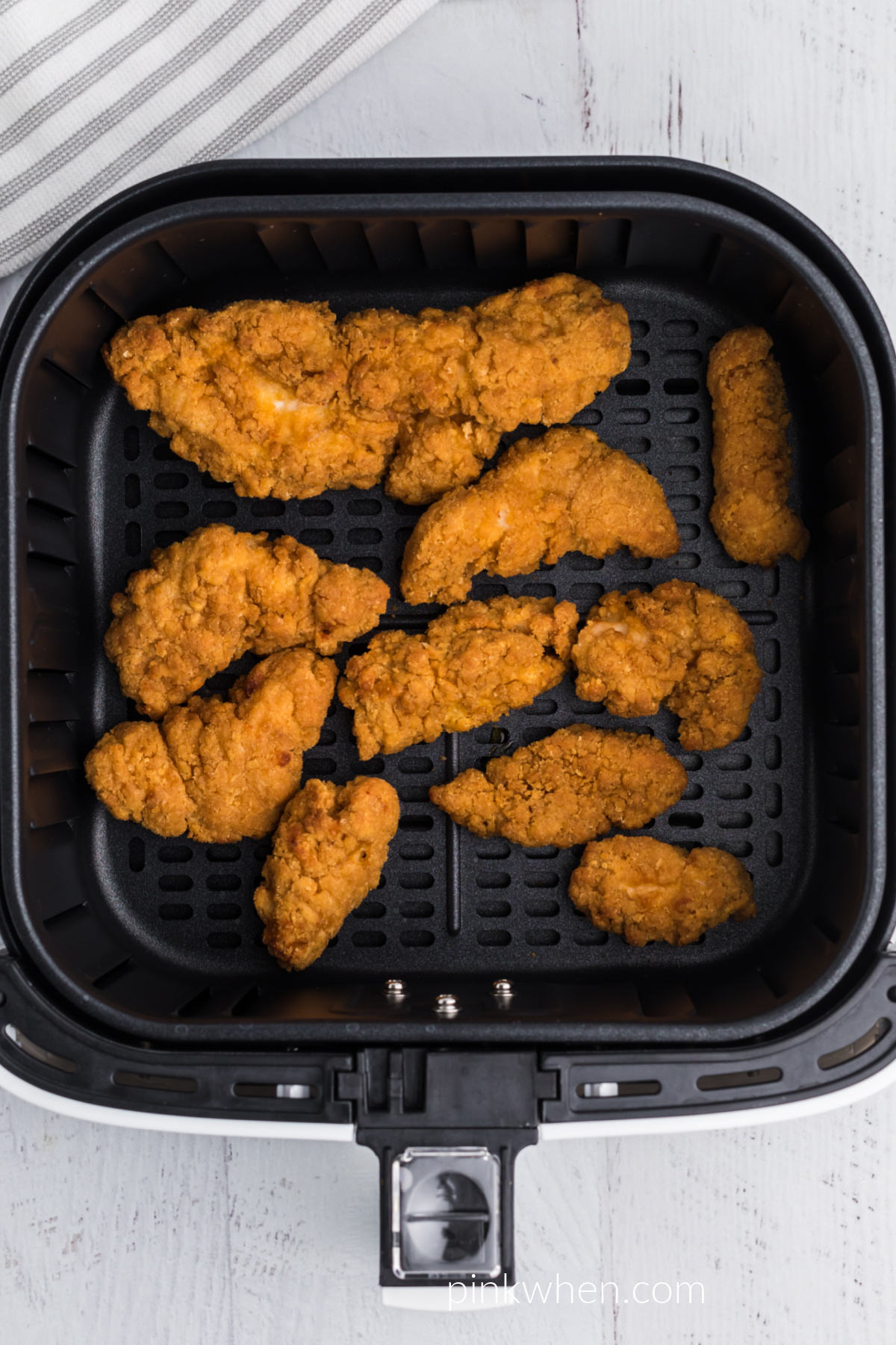 chicken strips fully cooked and in the basket of the air fryer, ready to serve.
