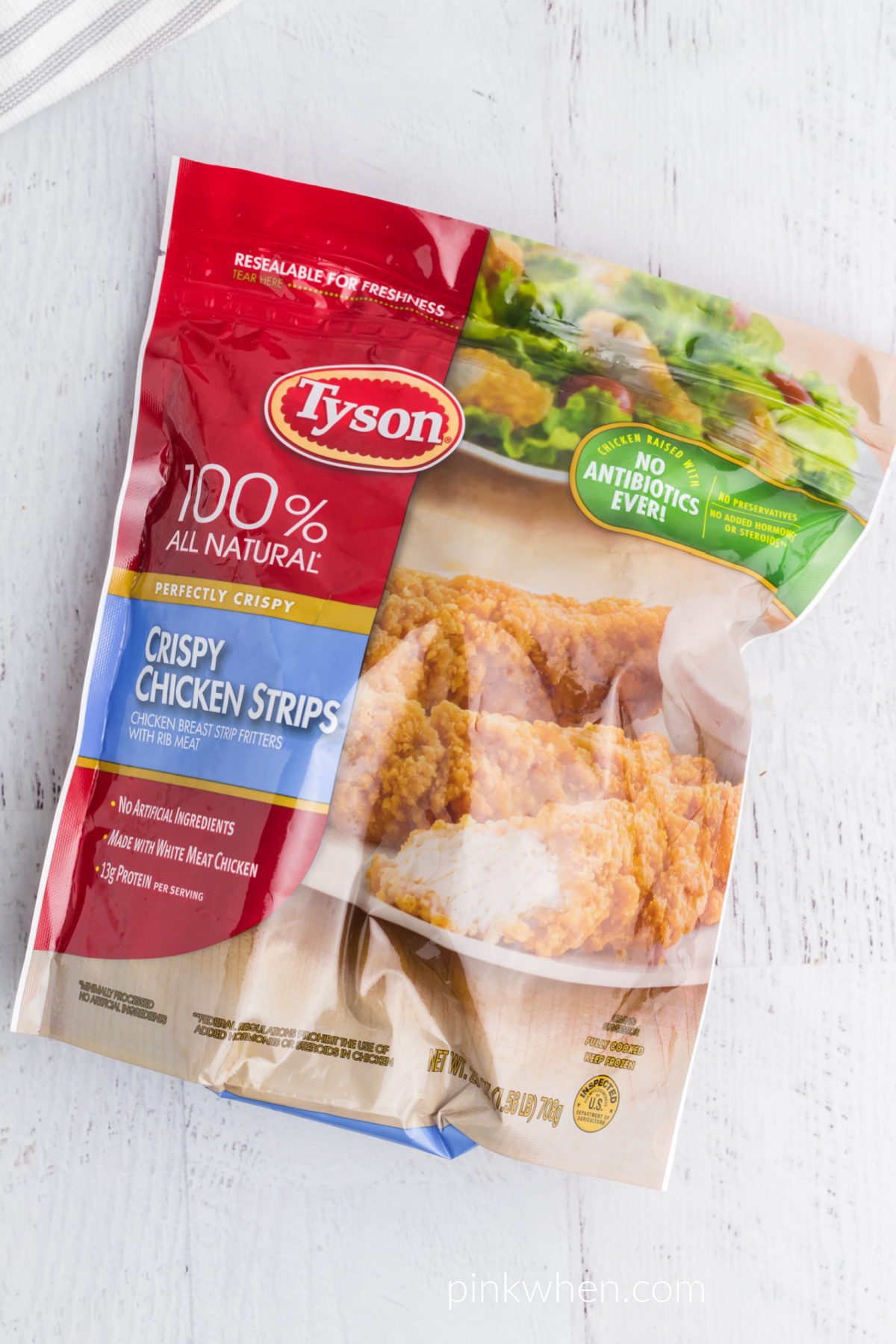 Package of Tyson frozen chicken strips on a white table. 