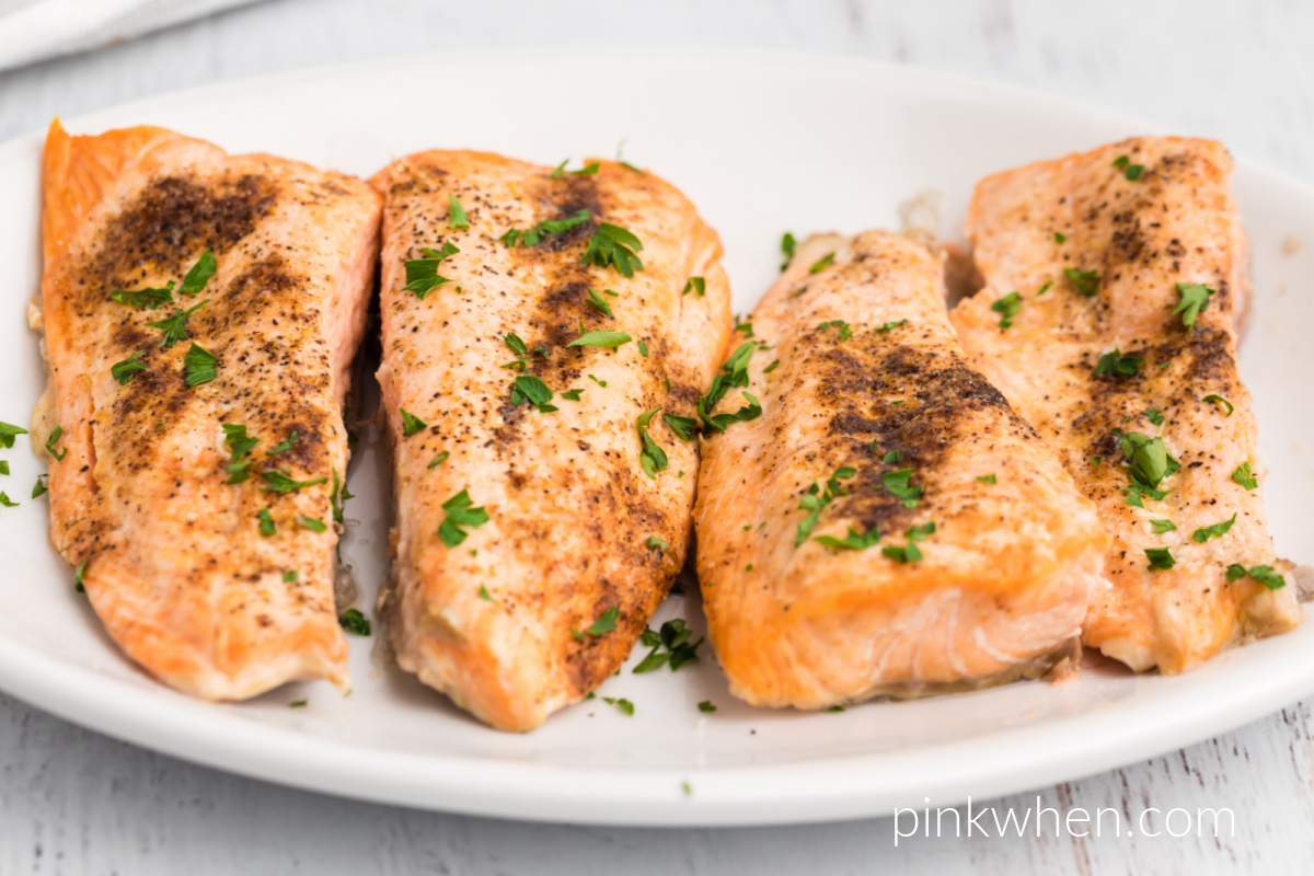 Salmon cut into smaller fillets and served on a serving platter ready to eat. 