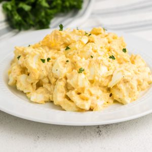 Egg salad garnished with parsley and served in a white bowl for serving.