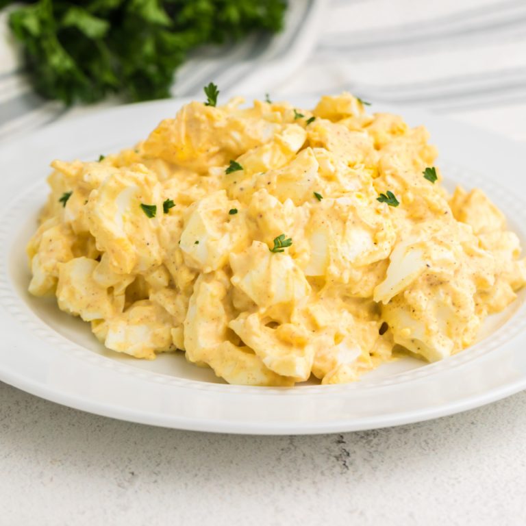 Egg salad garnished with parsley and served in a white bowl for serving.
