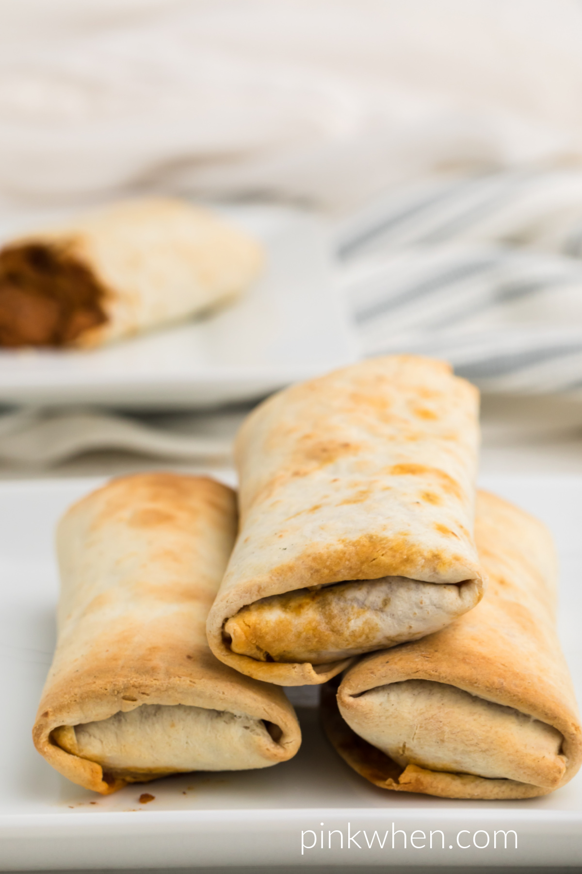 Air Fryer Burritos stacked on a white plate that were cooked from frozen. 