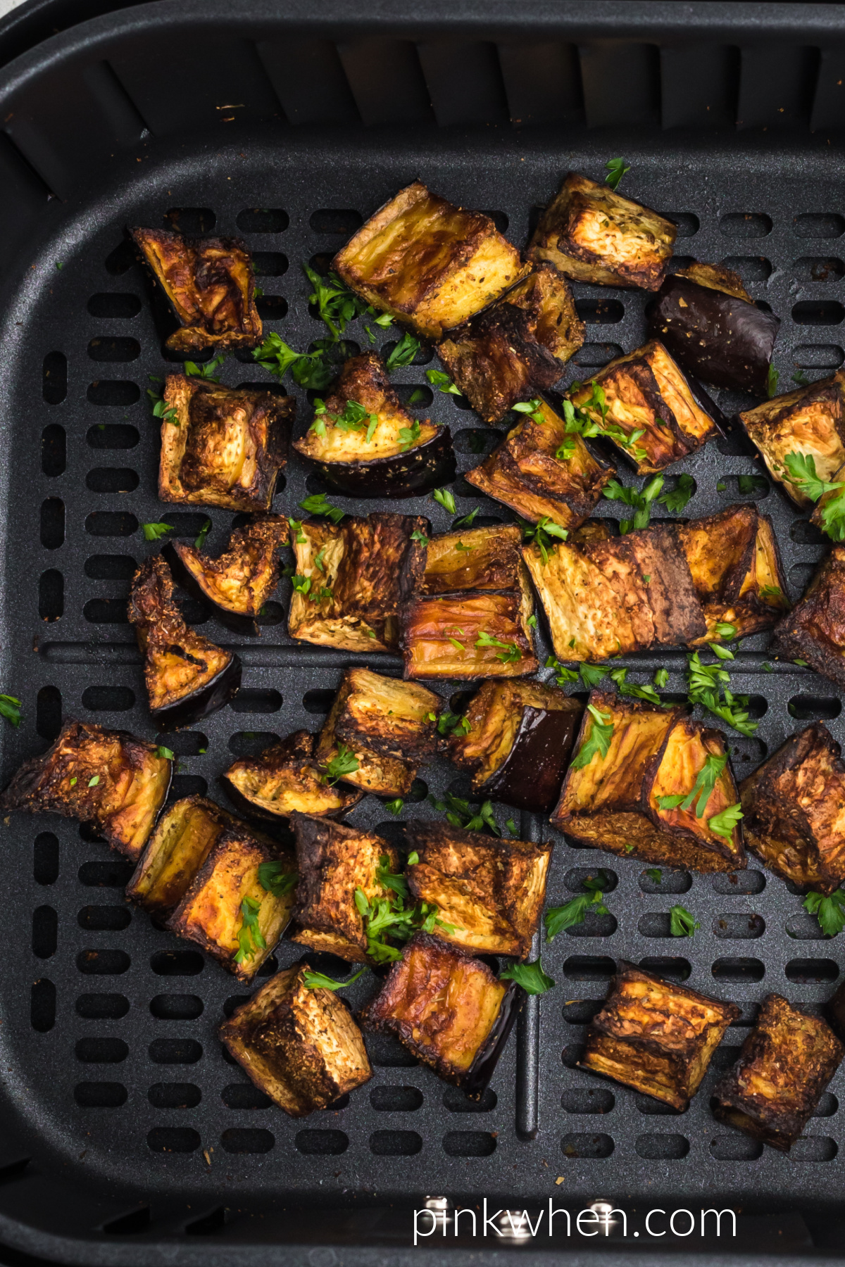 Crispy Air Fryer Eggplant topped with fresh parsley in the air fryer basket. 