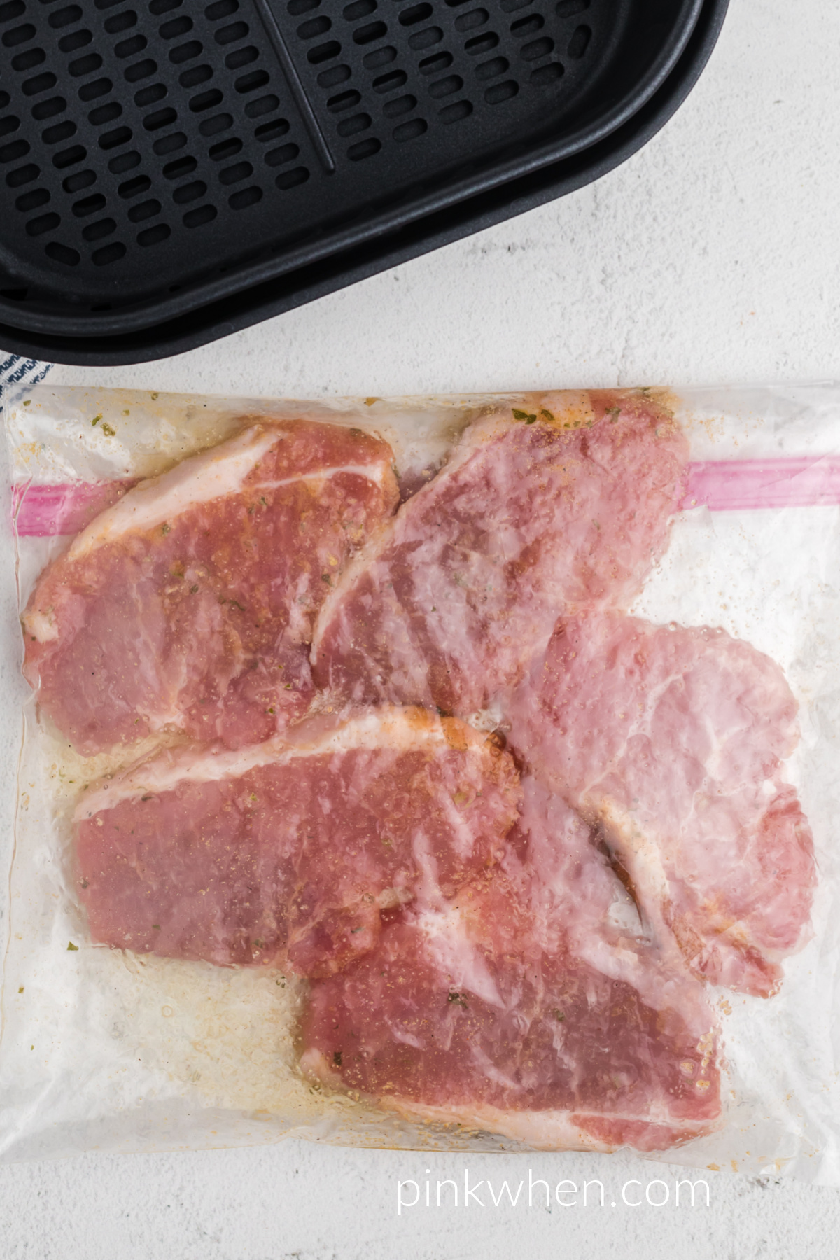 Seasoned pork chops in a bag ready to be placed into the air fryer.