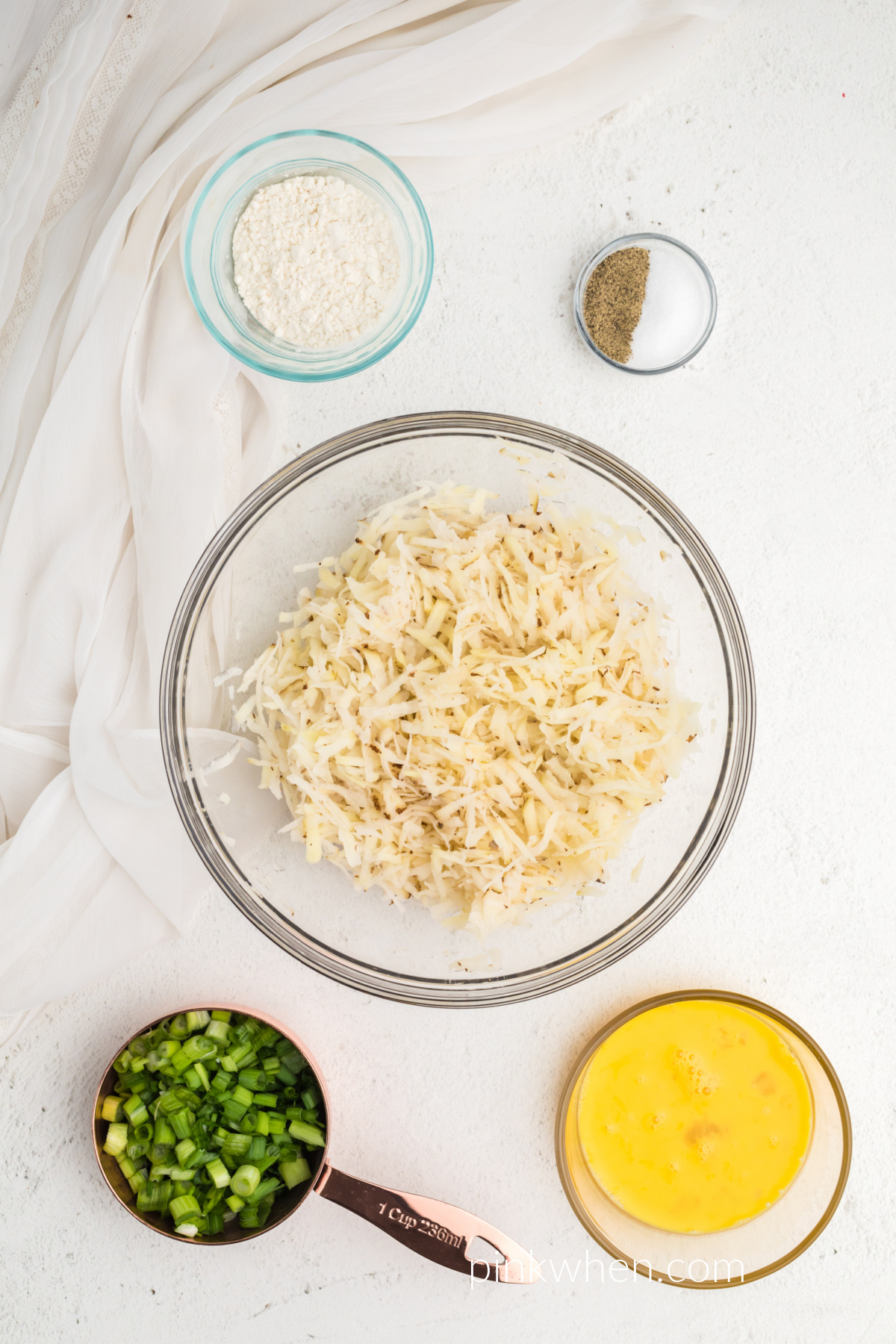 shredded potatoes drained of excess water in a dish ready to be made into fritters. 