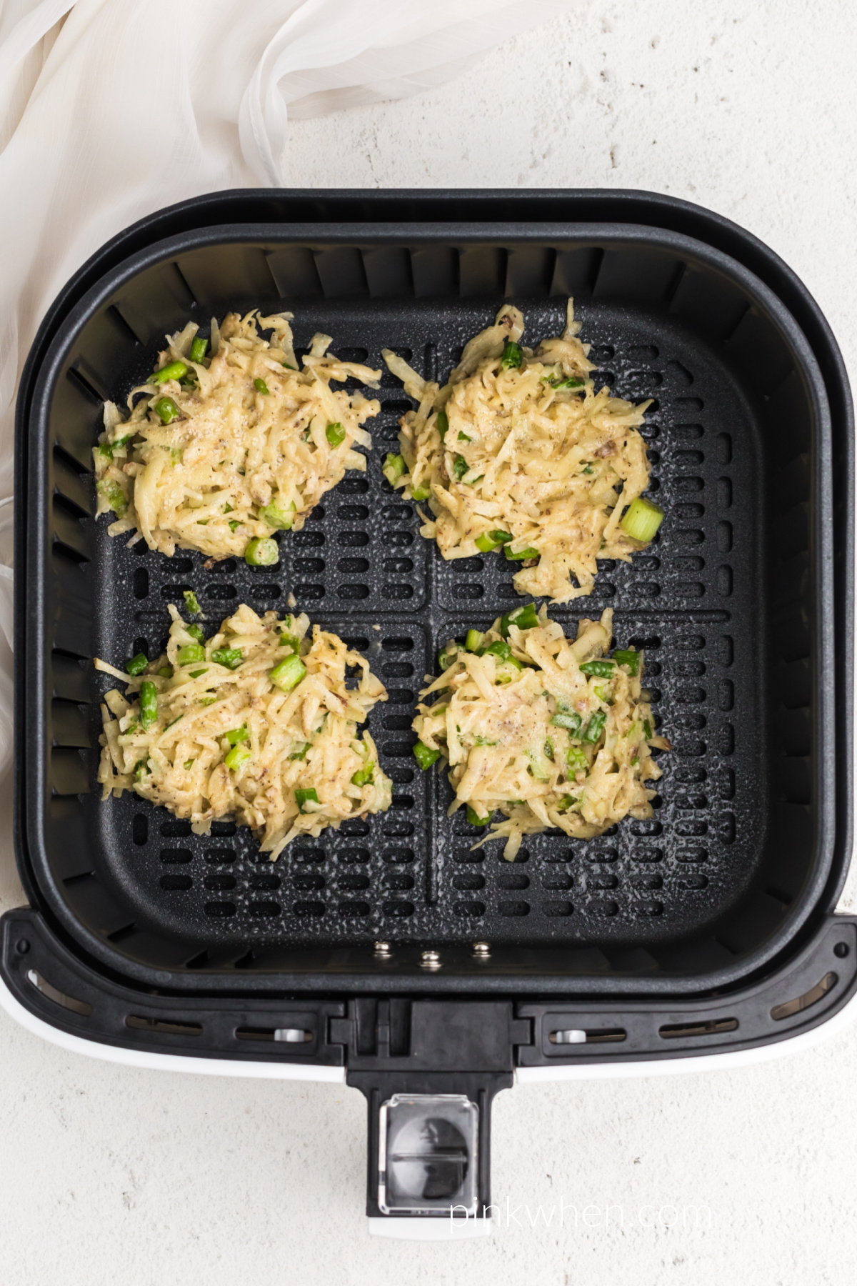 potato fritters in the air fryer basket ready to be cooked. 
