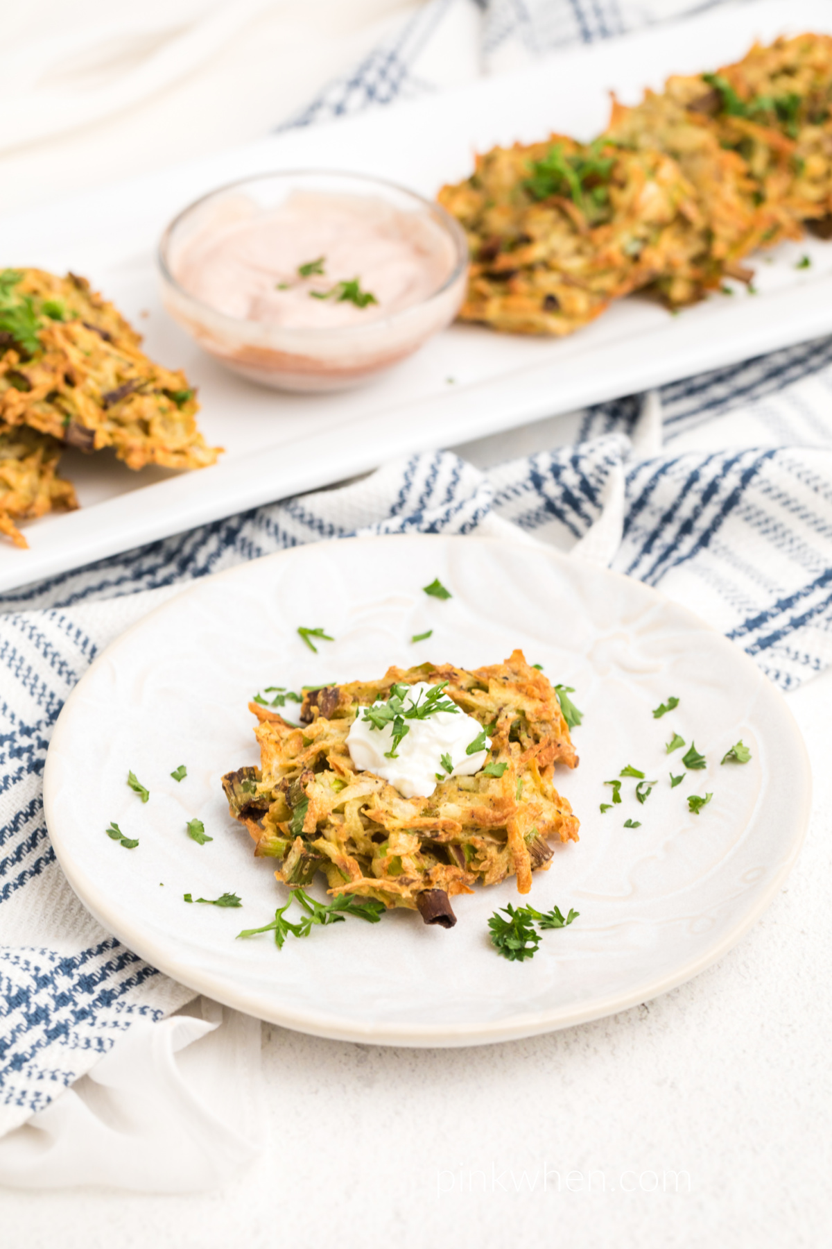 Potato fritters made in the air fryer served on a white tray and one on a plate ready to eat. 