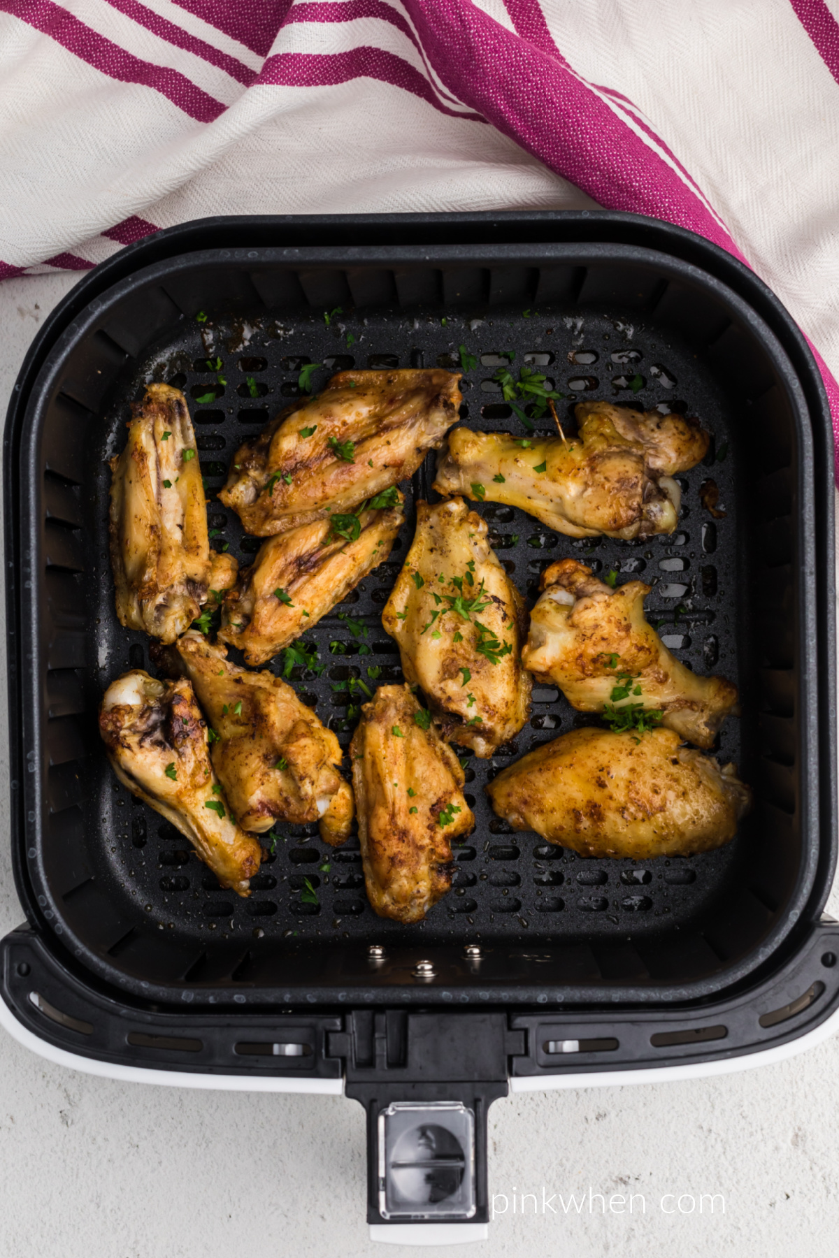 Seasoned chicken wings in the basket of the air fryer. 