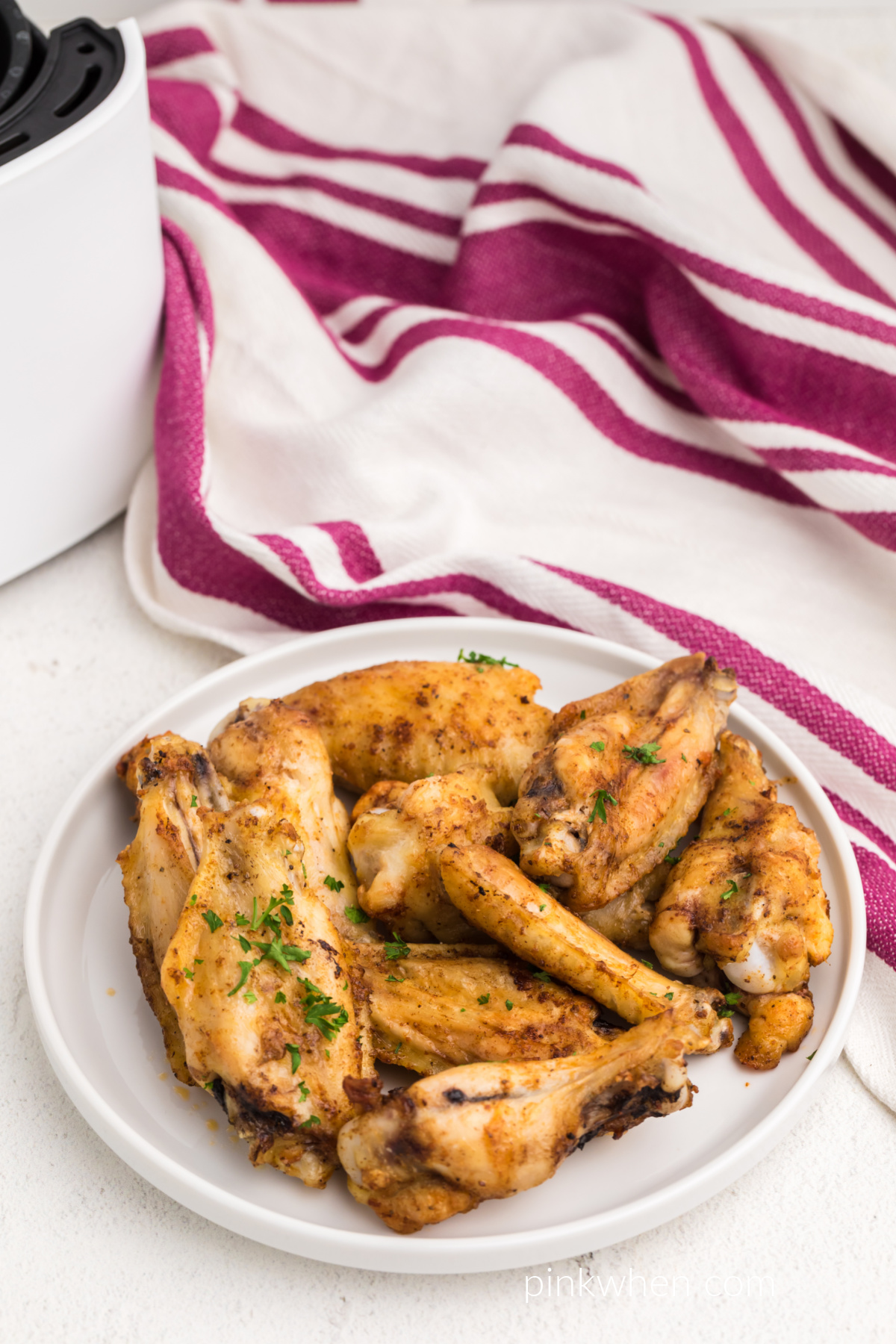 Chicken wings made from frozen in the air fryer that are seasoned and served on a white plate. 