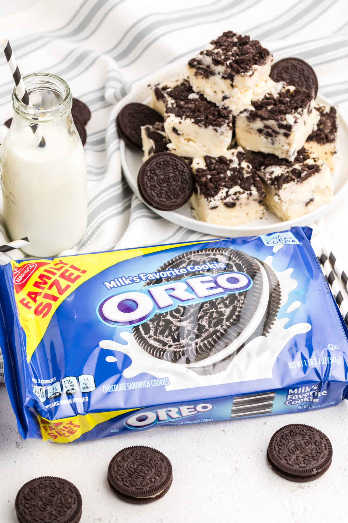 OREO fudge cut into squares in the background with a glass of milk and a package of OREO cookies in the foreground. 