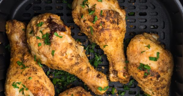 Overhead shot of seasoned air fryer drumsticks in the basket of the air fryer.