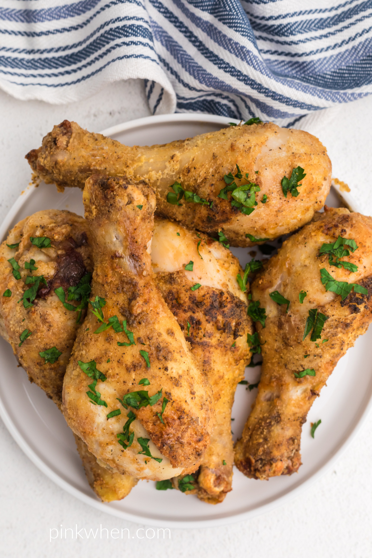 Overhead shot of air fried drumsticks seasoned and served on a white plate.