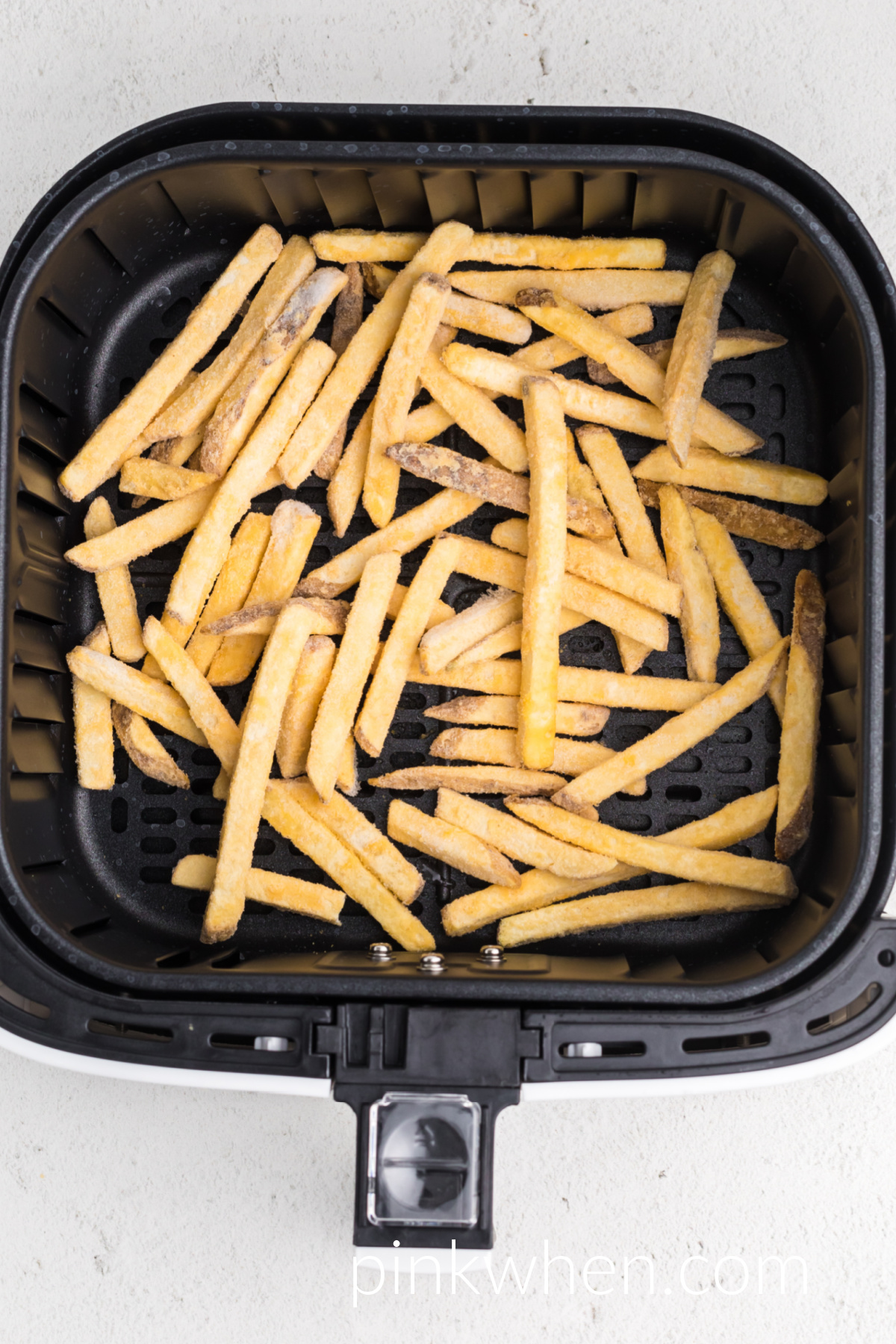 frozen french fries in the basket of the air fryer.