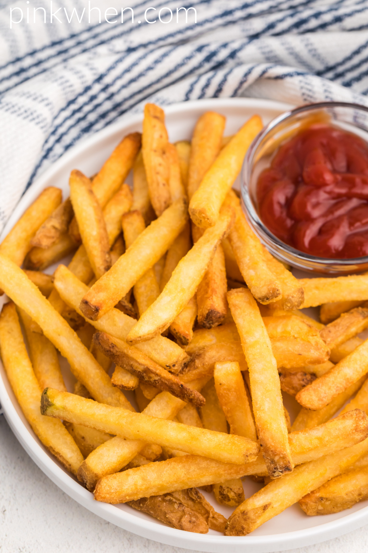 Plate of french fries on a white plate made in the air fryer and ready to serve.