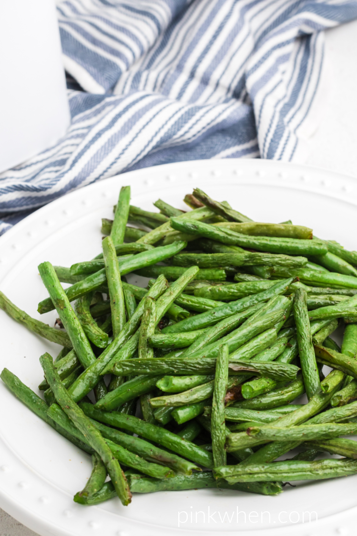 Air fried green beans on a white plate ready to serve. 