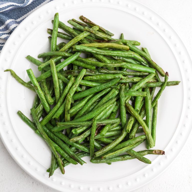 Air fried green beans on a white plate and ready to eat.