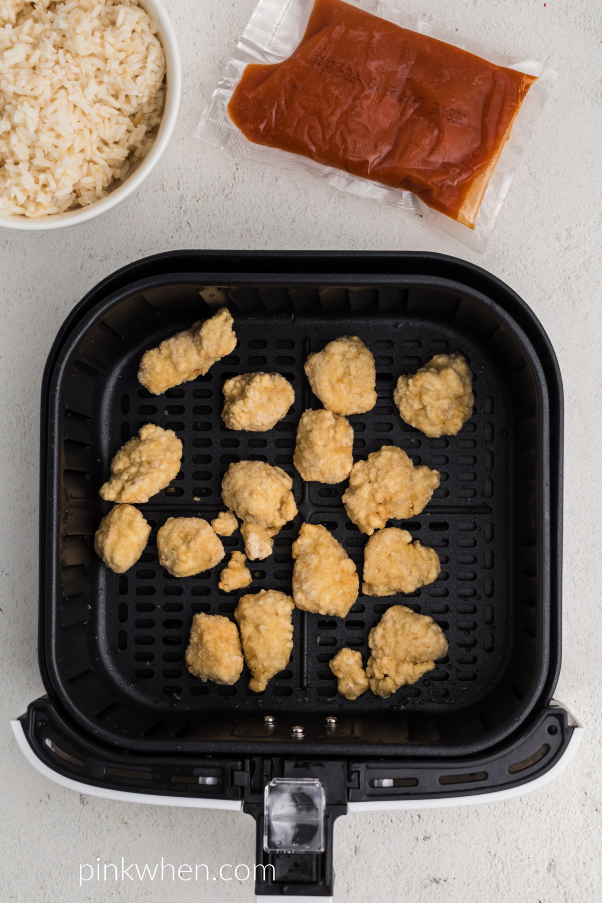 Frozen Orange Chicken in the air fryer basket ready to be cooked. 