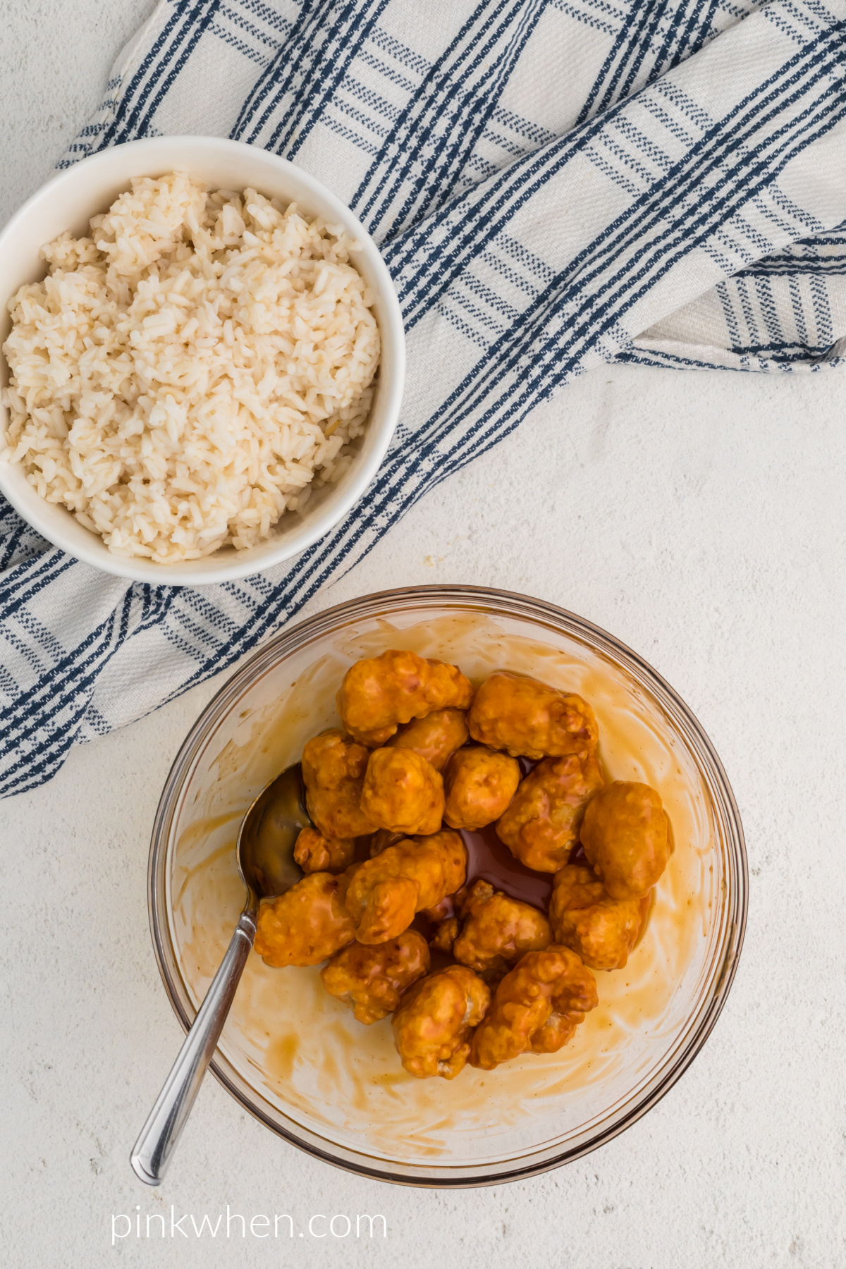 Chicken cooked and topped with orange sauce in a bowl before adding it back to the basket to finish cooking.
