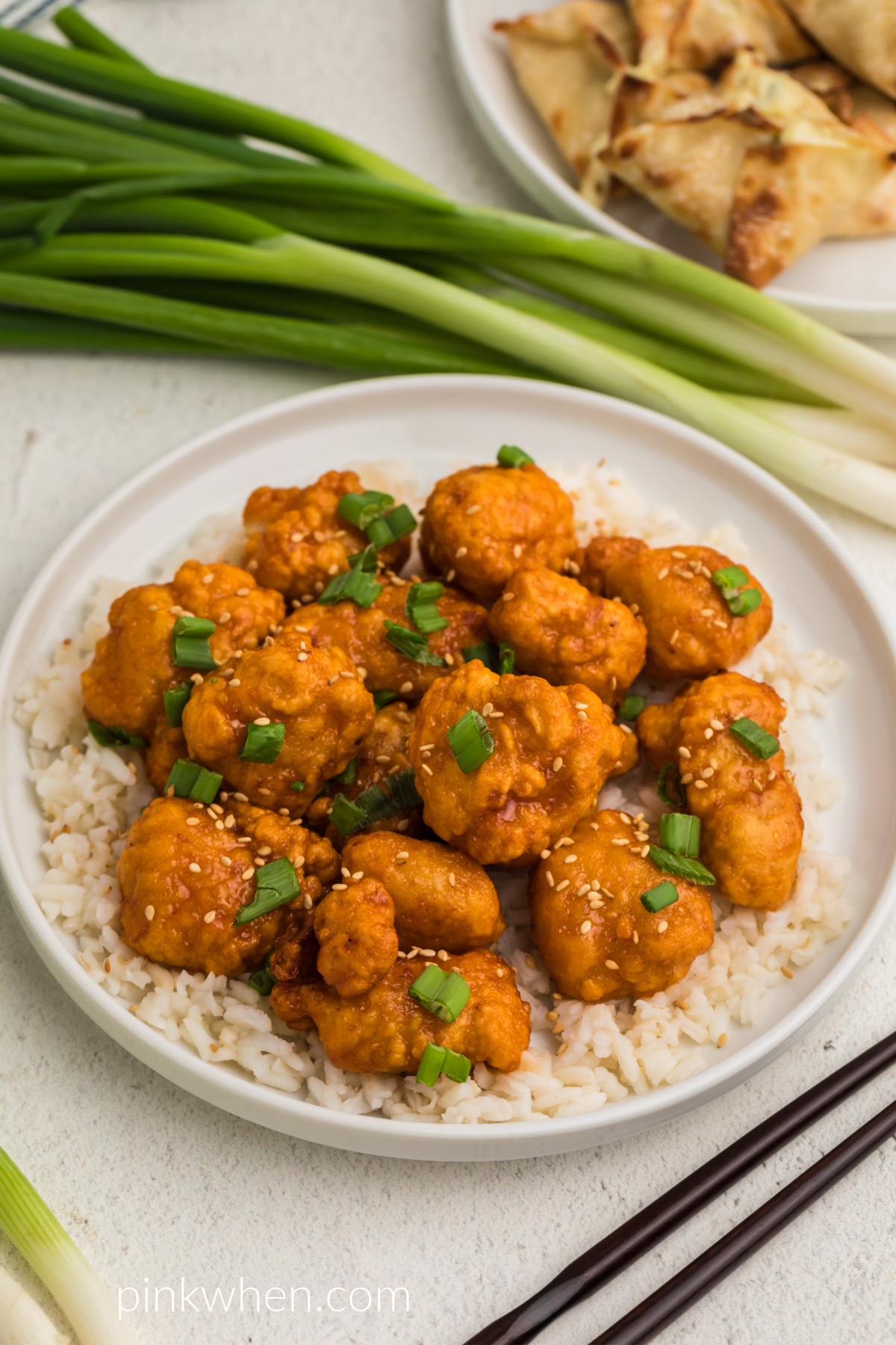 Air fryer orange chicken over rice on a white plate ready to eat. 