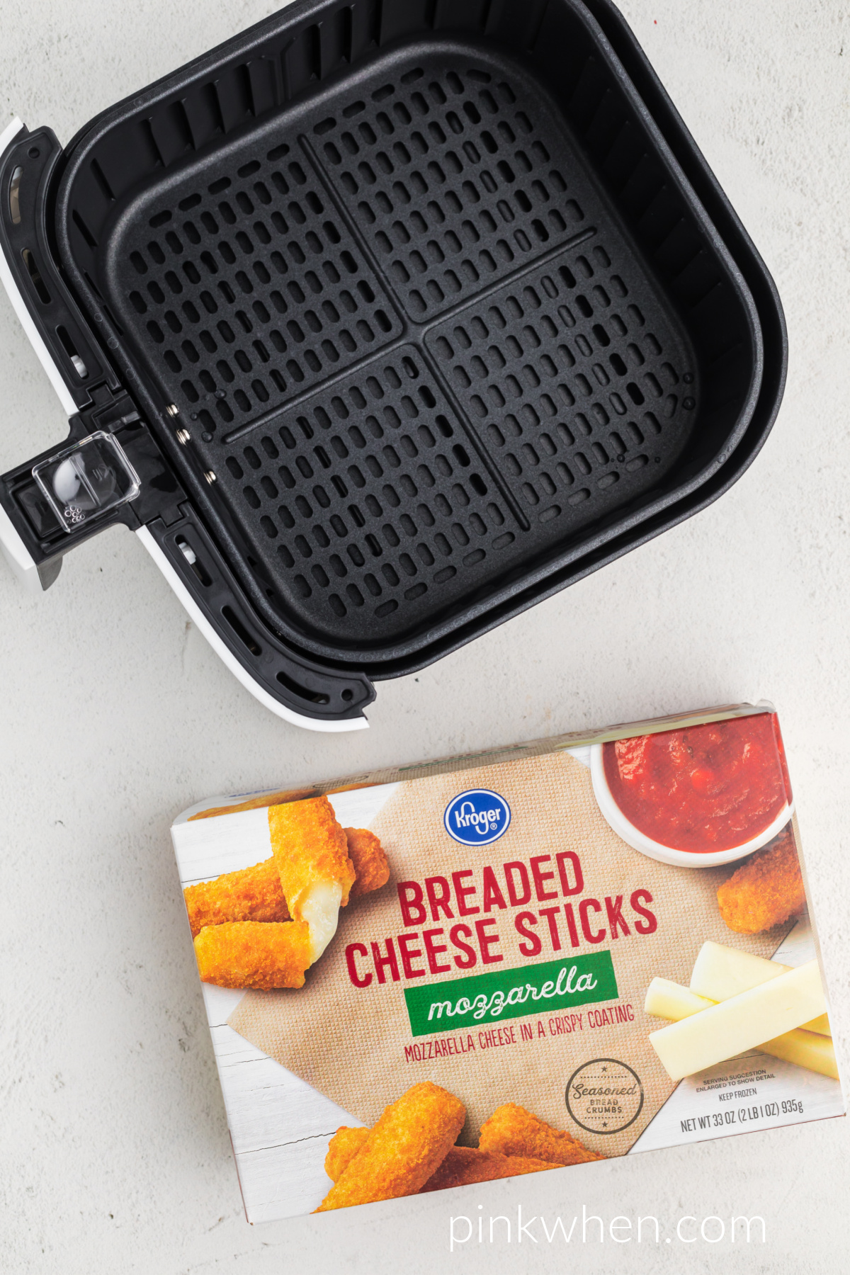 frozen mozzarella sticks in a box next to an air fryer basket. 