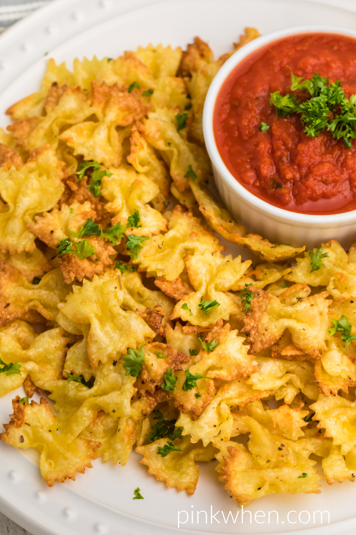 Close up of pasta chips made in the air fryer, topped with fresh parsley, and ready to dip in sauce and serve.
