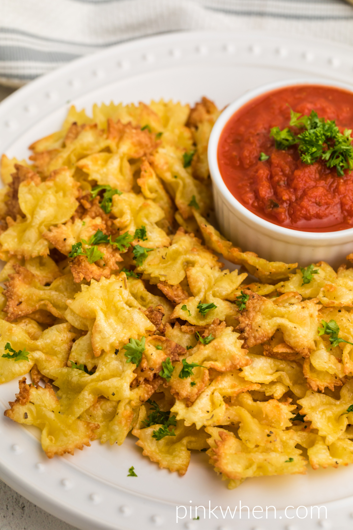 Air Fried Pasta chips on a white plate topped with fresh parsley, ready to serve.
