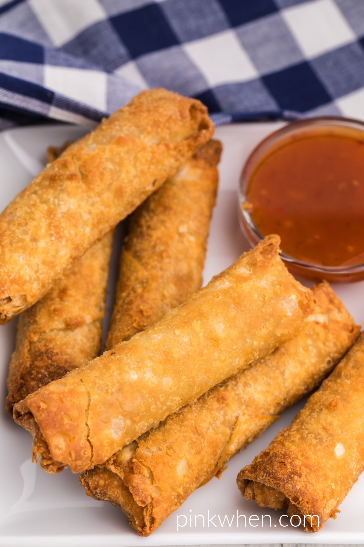 Close up photo of air fried frozen egg rolls on a white plate. 