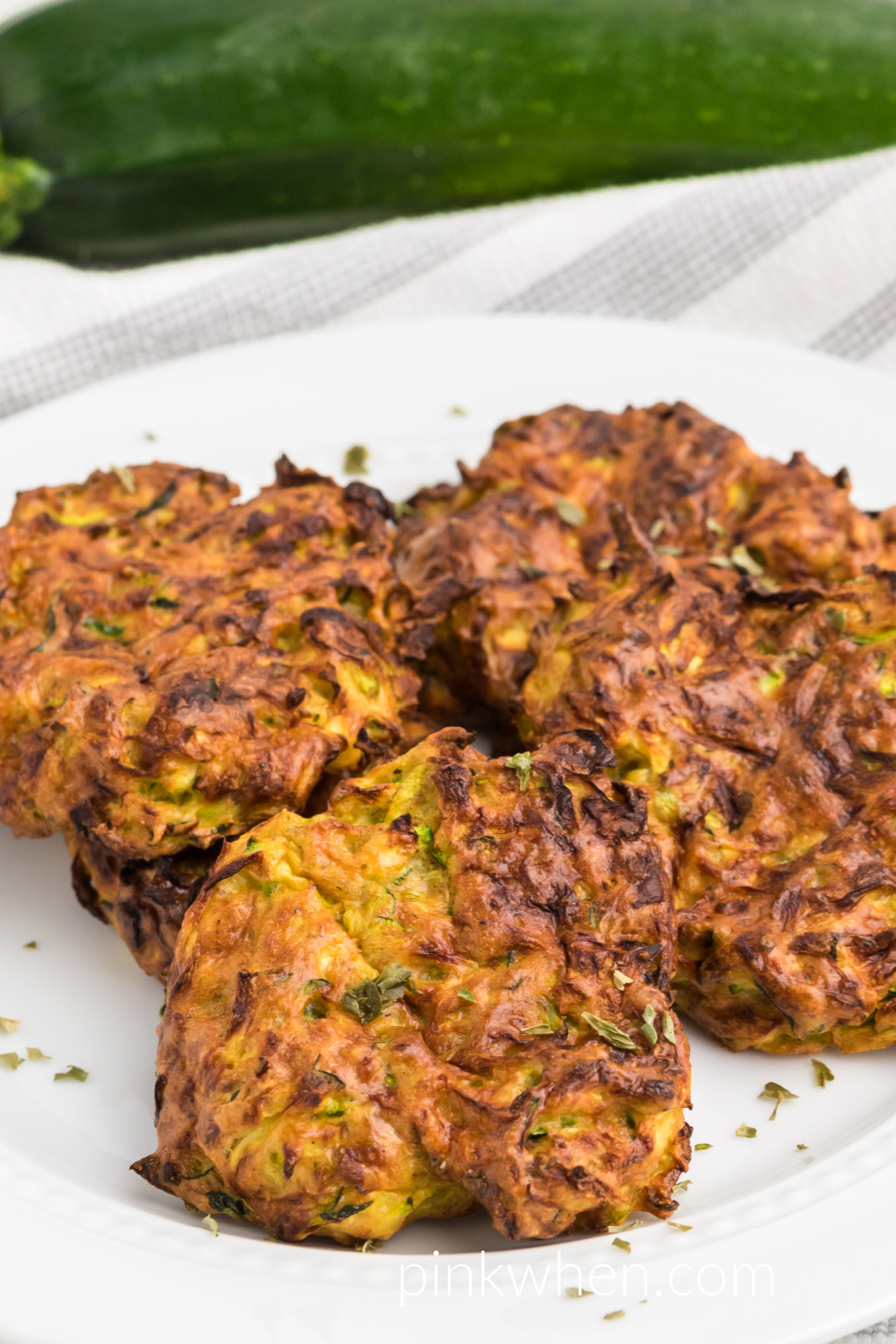 Air fried zucchini fritters on a white plate ready to serve. 