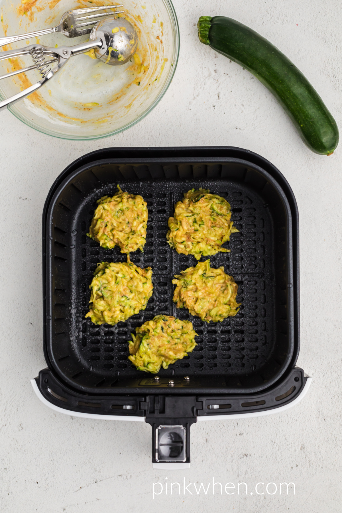 Zucchini mixture scooped onto the prepared air fryer basket, ready to cook. 
