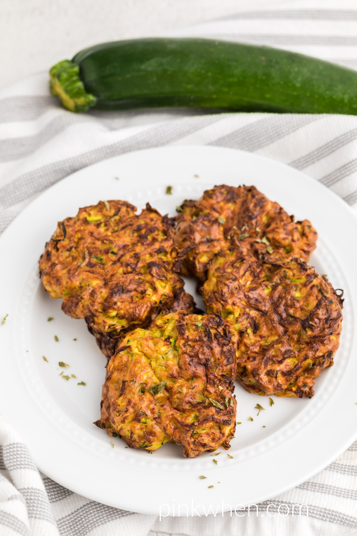 Air fried zucchini fritters on a white plate, ready to serve. 