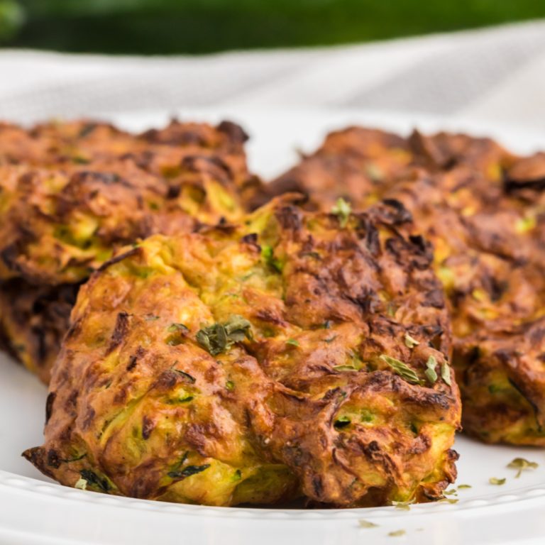 Close up photo of zucchini fritters made in the air fryer and on a white plate.