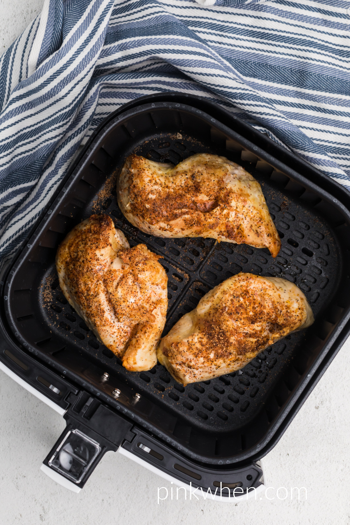 frozen chicken breasts in the basket of the air fryer.