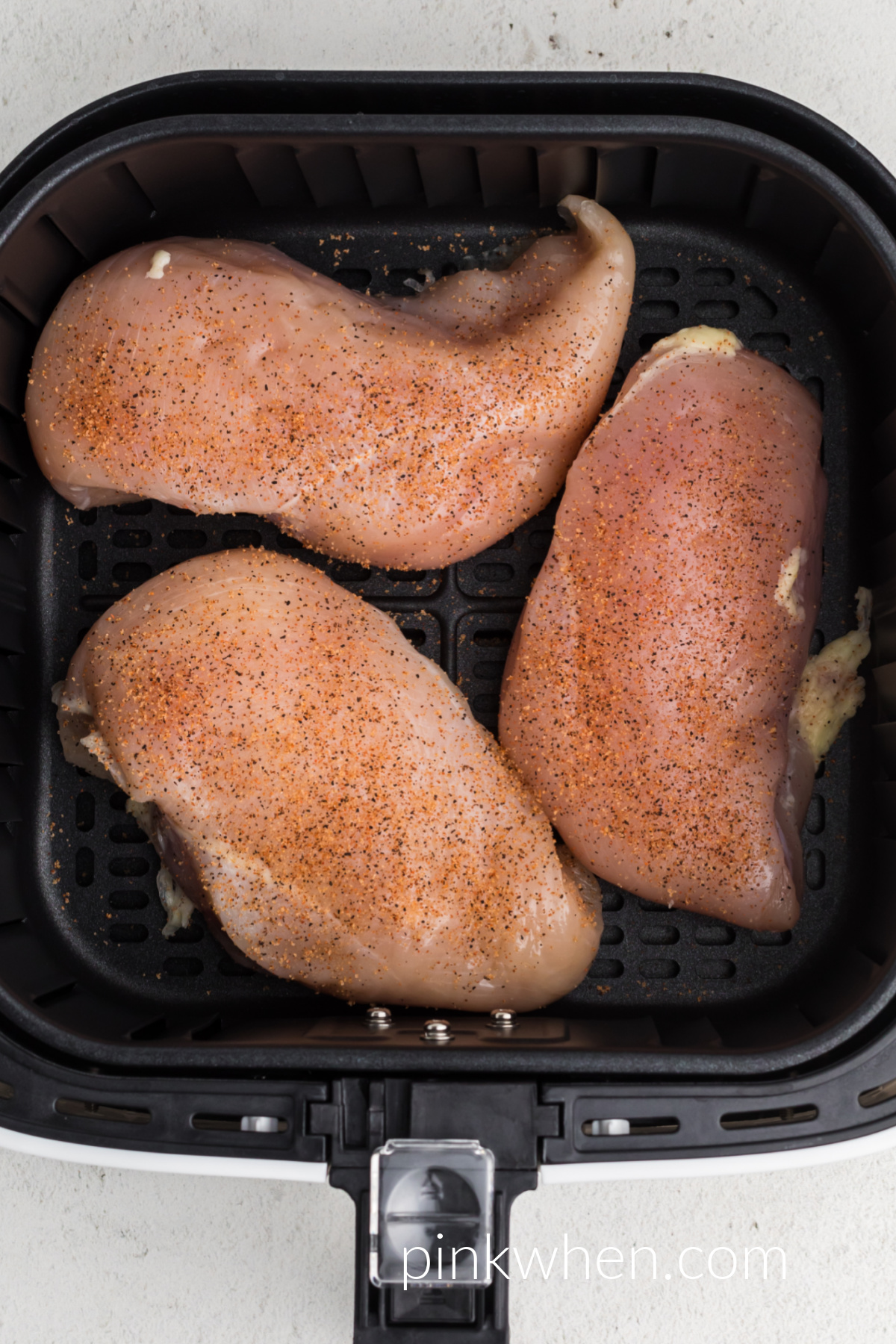 seasoned frozen chicken breast in the air fryer basket.
