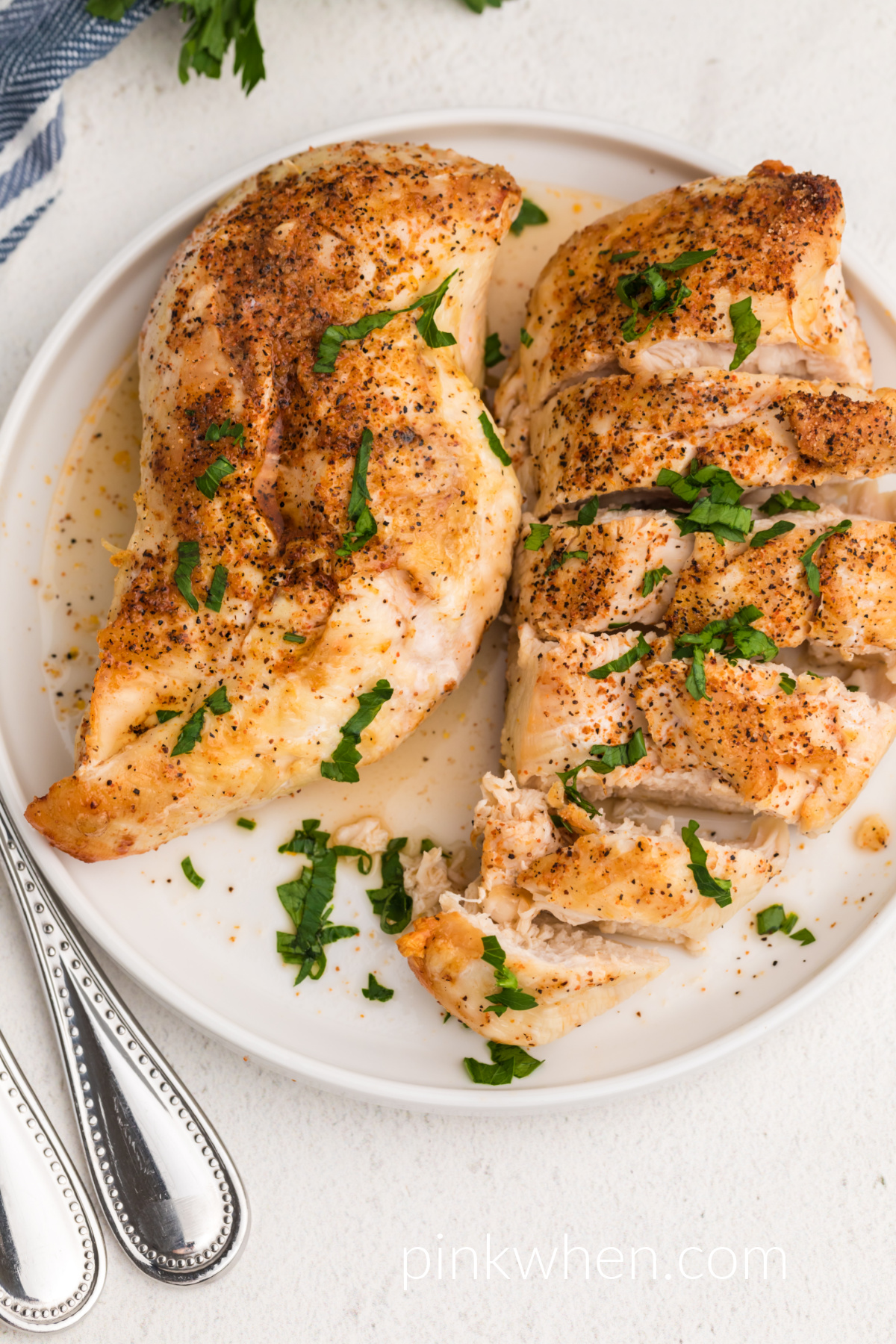 Fully cooked and seasoned frozen chicken breast made in the air fryer, sliced and served on a white plate. 