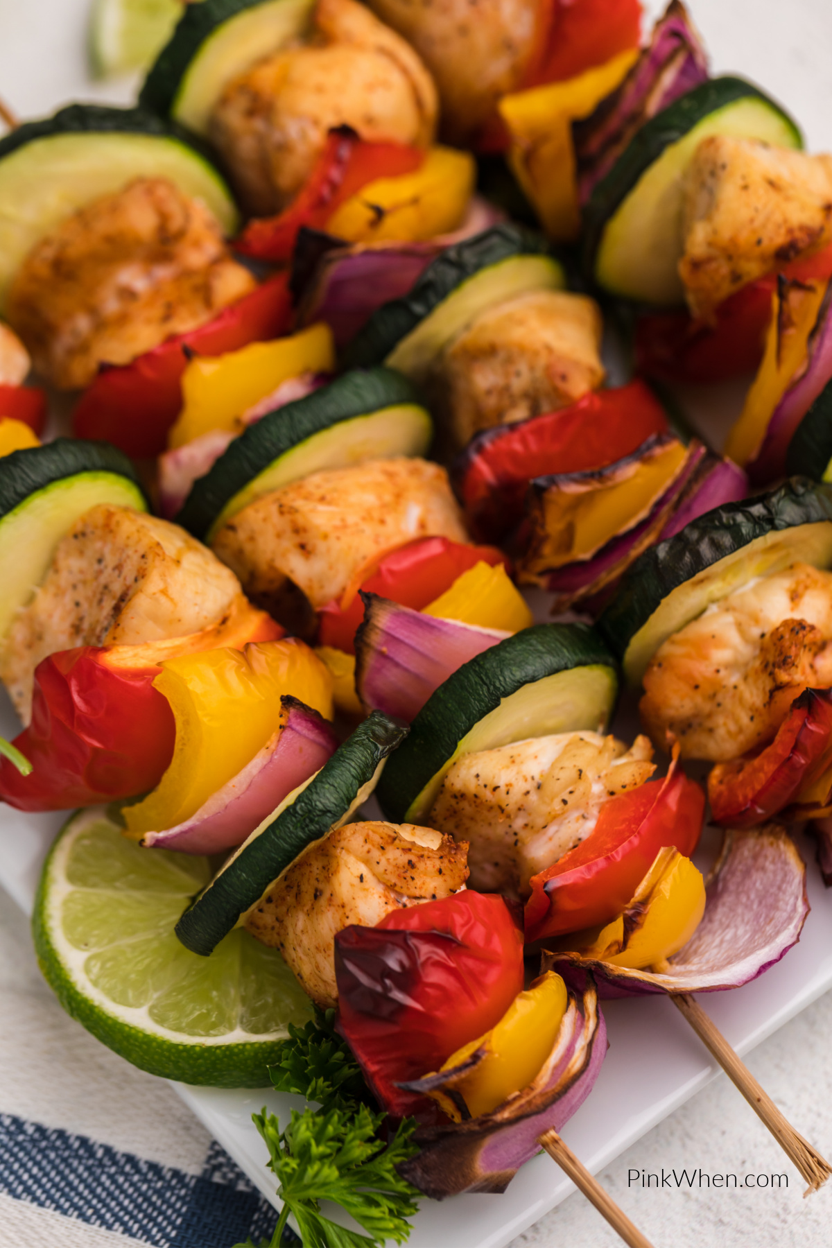 Close up photo of air fried chicken skewers on a plate served with sliced limes.