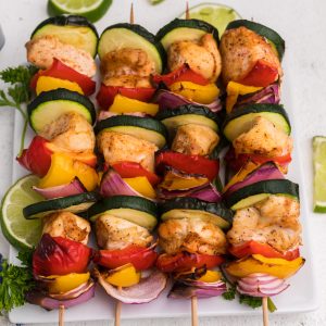 Air Fryer Chicken Kabobs on a white plate with sliced limes.