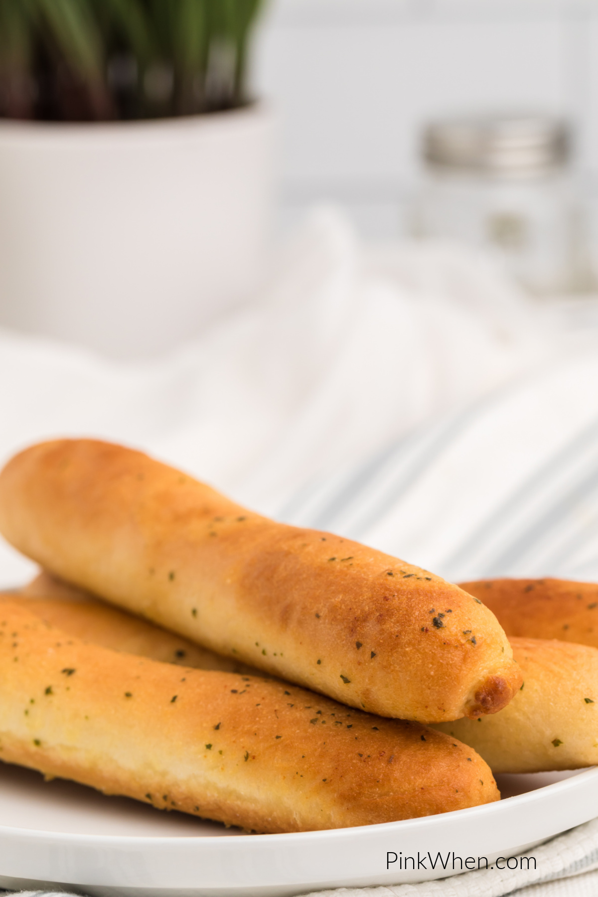 Close up photo of breadsticks made in the air fryer from frozen on a white plate.