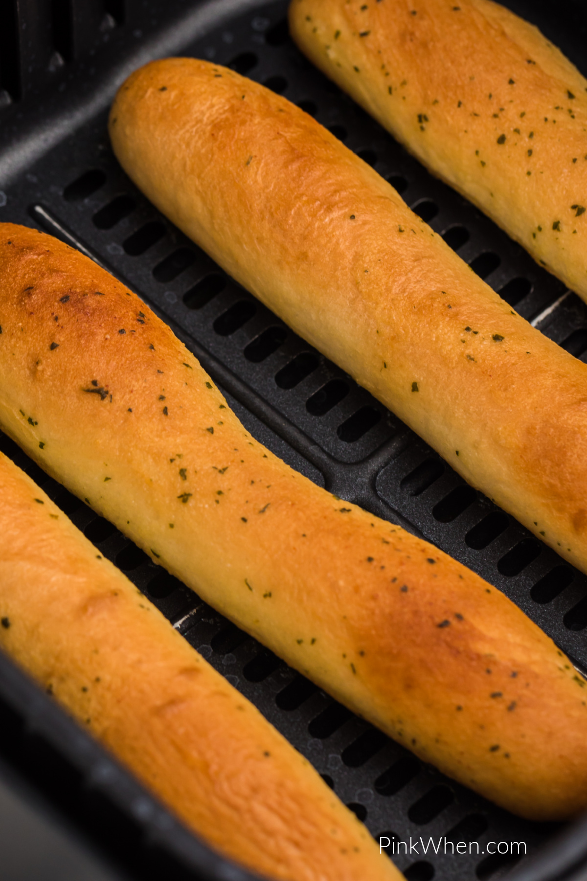 Close up photo of air fried breadsticks in the basket of the air fryer.