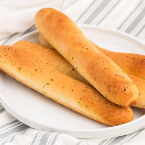 Breadsticks on a white plate that were air fried from frozen.