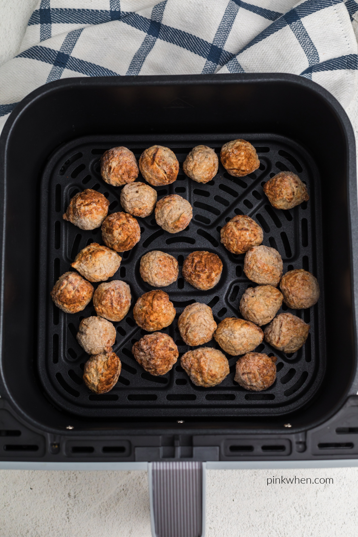 Frozen meatballs in air fryer basket. 