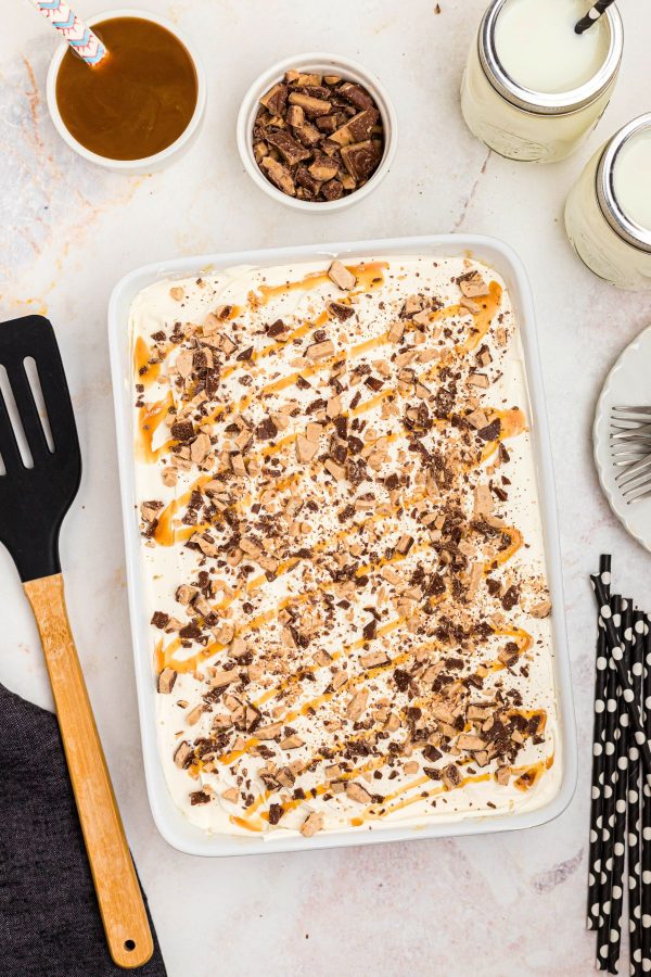White rectangle cake with milk and spatula on a white marble table. 