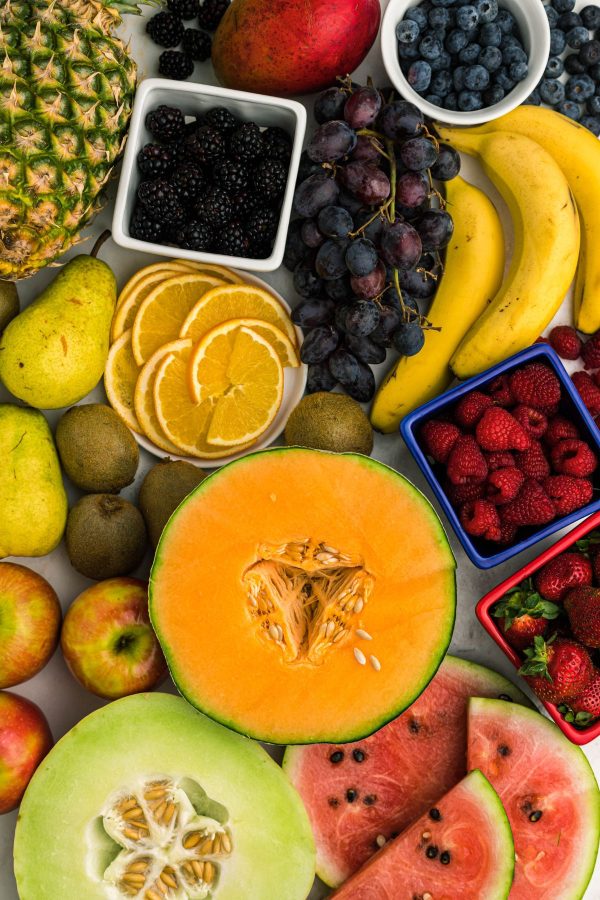 Various fruits on a white marble table before being cut into pieces.