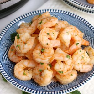 Orange shrimp on a blue plate in front of an instant pot