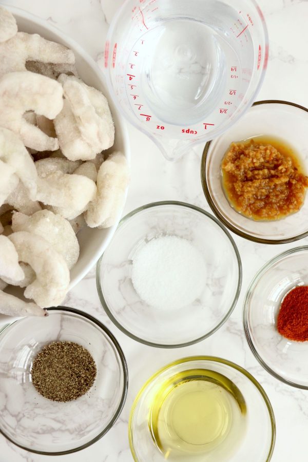 Ingredients measured out in clear glass bowls on a white marble table. 