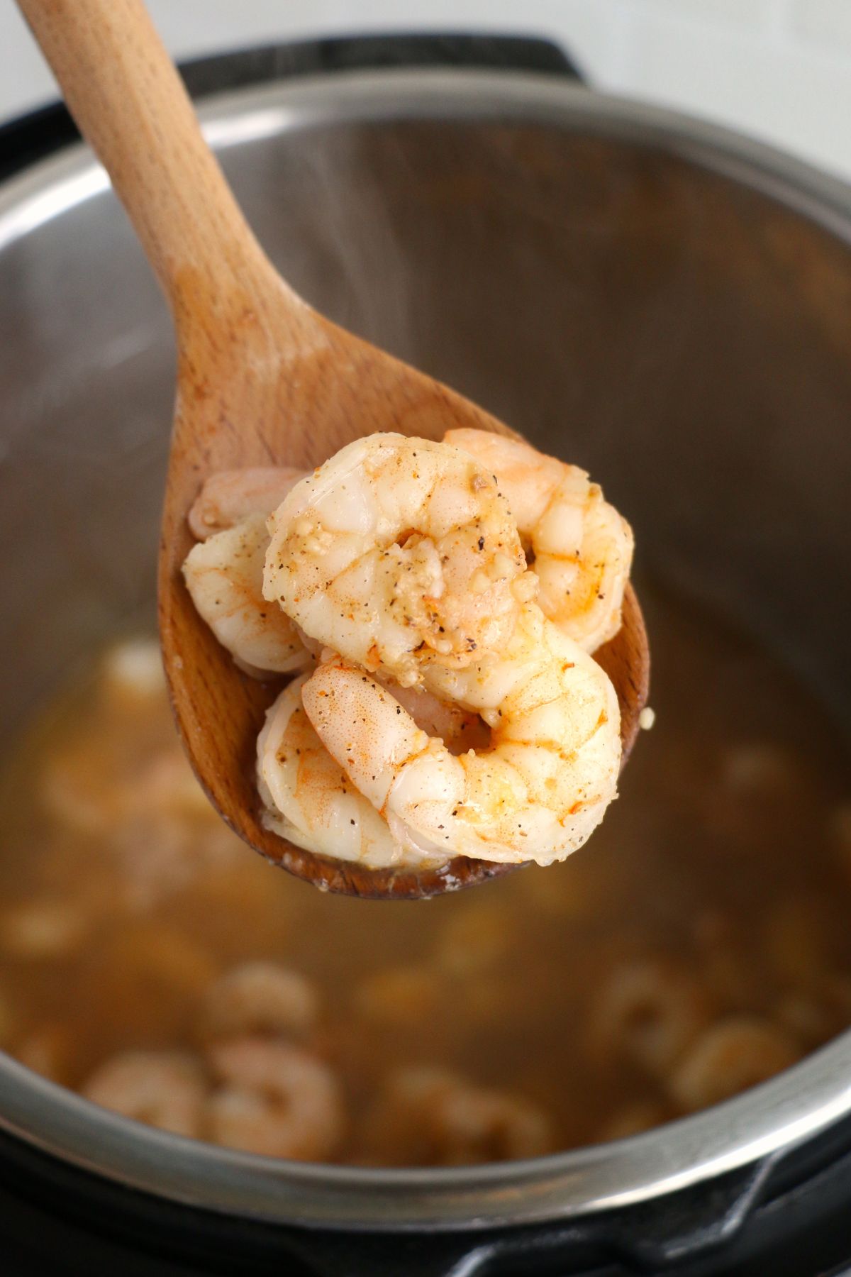 Orange juicy shrimp being spooned out of Instant pot after being cooked. 