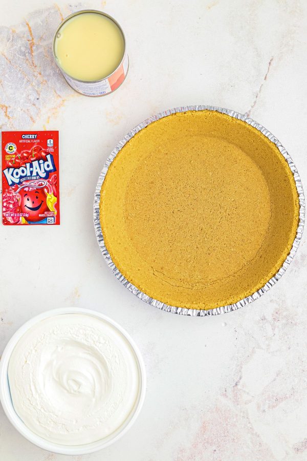 Ingredients needed to make kool aid pie on a white marble table.