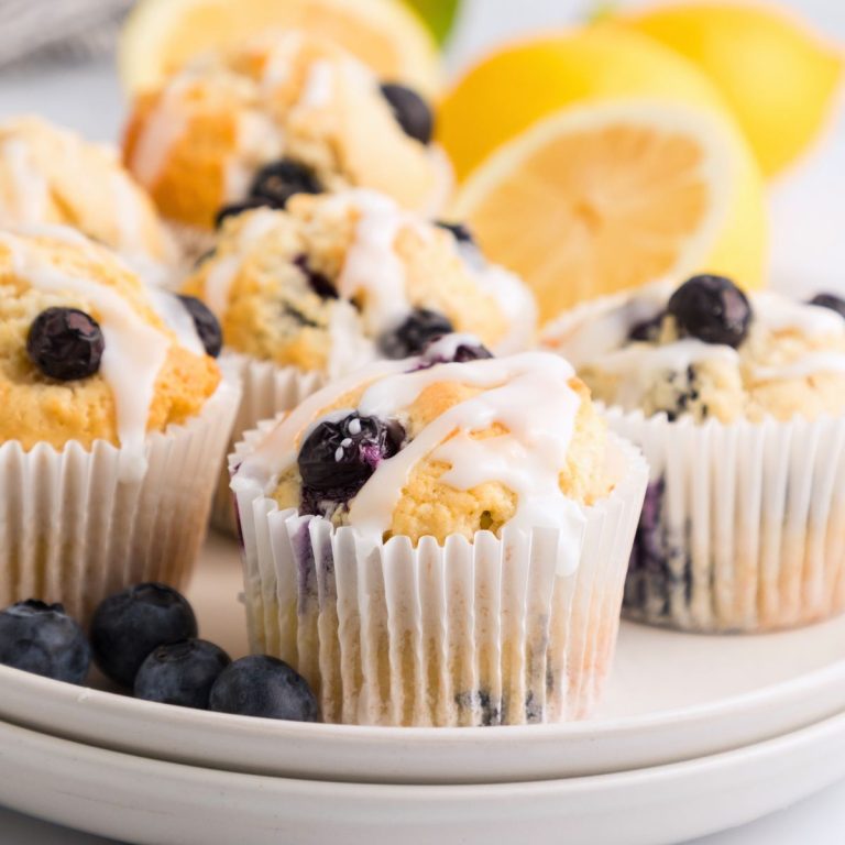 Golden lemon blueberry muffins on a white plate with lemon slices